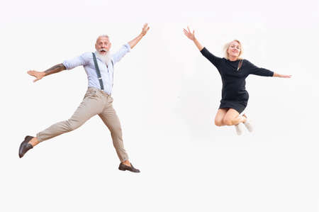 happy girl and senior man jumping, white wall in background
