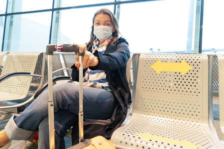 woman in the airport wearing mask during pandemic outbreak, reading mobile phone, new normal concept
