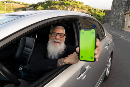 Senior man in car showing phone with green screen
