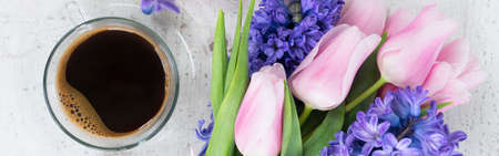 Pink tulips and blue hyacinths fresh flowers with cup of coffee, holiday breakfastの写真素材