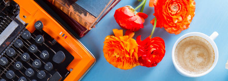 Workspace with orange retro typewriter with flowers and coffee, copy space on blue background