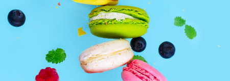 Assorted macaroons falling cookies with berries close up on blue background