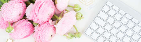 Flat lay home office workspace - modern white keyboard with female accessories and ranunculus...