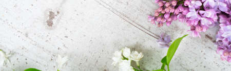 Fresh light lilac flowers frame over white wooden background with copy space, flat lay spring floral...