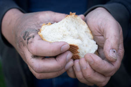 Concept of a hunger, close up of a hsnds of refugee holding breadの写真素材