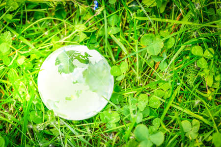 earth protection and sustainable ecology development concept - glass earth planes on green lush background with sunshineの写真素材