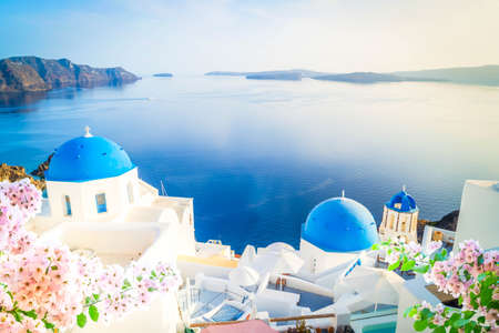 white church belfry, blue domes and volcano caldera with sea landscape, beautiful details of Santorini island, Greece with sunshineの写真素材