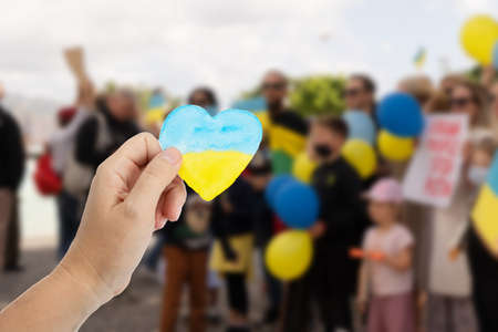 Hand holding heart in colors of Ukranian flag, the rally against war. Support for Ukraine. No war.の写真素材