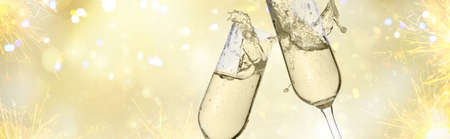 Two festive champagne glasses on golden bokeh background with lights and fireworks, web banner formatの写真素材