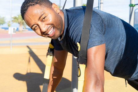 Sport workout of happy african american men making trx training on outdoor sports gound
