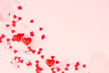 Valentines day festive background with scettred hearts over pink background with copy space