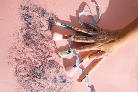 Minimal modern cosmetic scene with set of make up brushes set over pink background with glitter and shadow overlayの写真素材