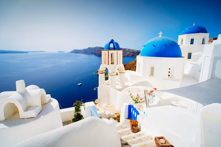 traditional greek village Oia of Santorini, with blue domes against sea and caldera with sunshine, Greeceの写真素材