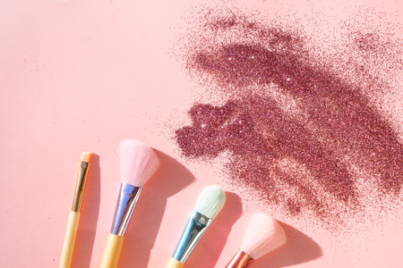 Minimal modern cosmetic scene with set of make up brushes set over pink background with glitter and shadow overlayの写真素材
