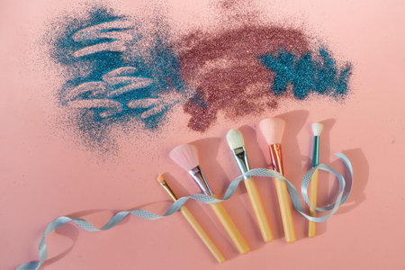 Minimal modern cosmetic scene with set of make up brushes set over pink background with glitter and shadow overlayの写真素材