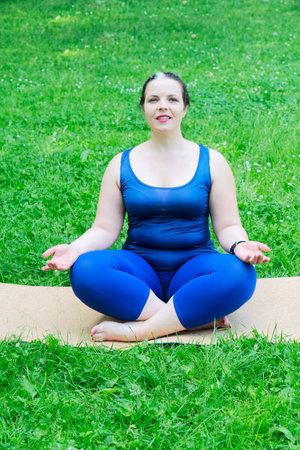 Woman and sports, exercise for weight loss and relaxation in the fresh air. Happy curvy 40s woman doing workout yoga routine outdoor at city parkの写真素材