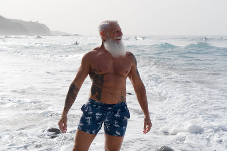 Happy fit senior man having fun buthing in the sea. Elderly people lifestyle and sport activityの写真素材