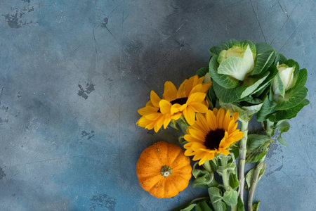 Bouquet of fall flowers and pumpkins on gray background, top view