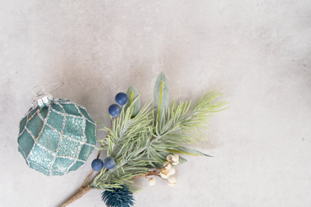 Christmas silver and teal decorations hanging on branch over gray background