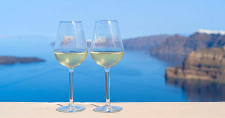 two glasses of white wine with Aegaen sea in background, Greeceの写真素材