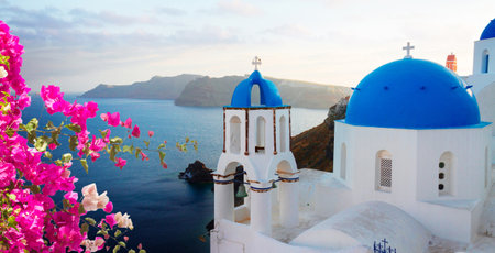 traditional greek village Oia of Santorini, with blue domes of churches in sunset light with flowers, Greeceの写真素材