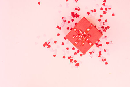 Valentines day festive background with pink hearts and red gift box on pink backgroundの写真素材