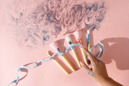 Minimal modern cosmetic scene with set of make up brushes set over pink background with glitter and shadow overlayの写真素材