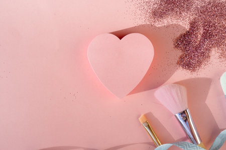 Minimal modern cosmetic scene with set of make up brushes set over pink background with glitter and shadow overlayの写真素材