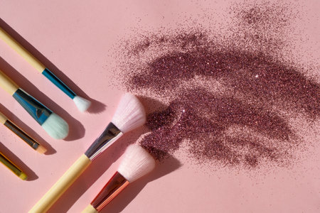 Minimal modern cosmetic scene with set of make up brushes set over pink background with glitter and shadow overlayの写真素材