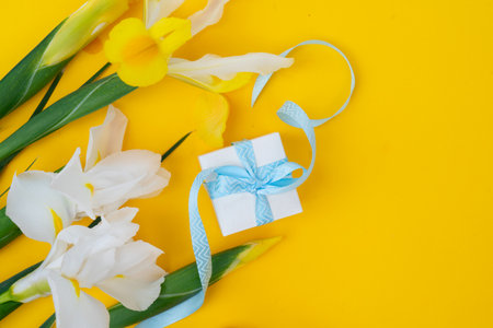 Irises flowers on bright yellow spring background, Easter festive background with gift boxの写真素材