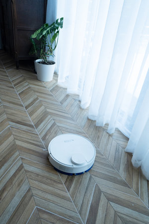 white modern robot vacuum cleaner at home interior on the floorの写真素材