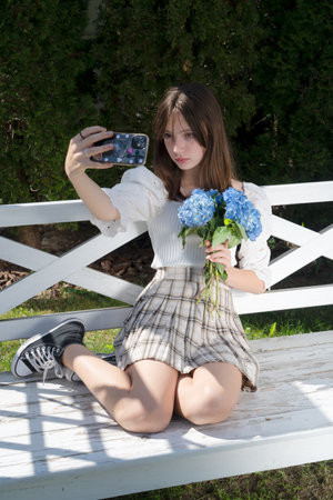 Teenager girl making selfie with flowers with her phoneの写真素材