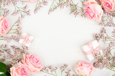 Rose fresh flowers with leaves and gift boxes frame on table from above with copy space, flat lay sceneの写真素材
