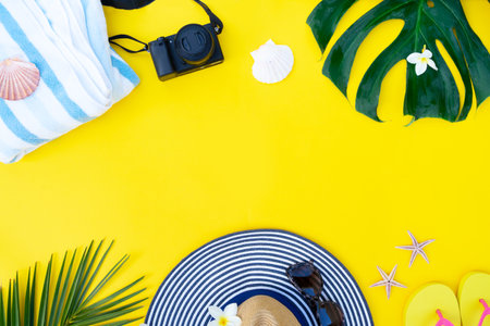Summer flat lay frame with hat and green leaves on yellow background with copy spaceの写真素材