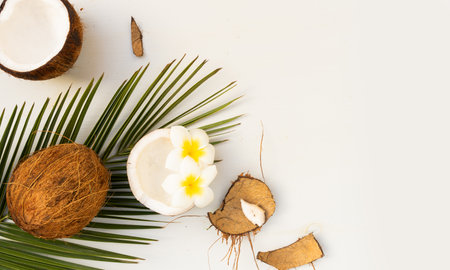 Summer flat lay scene with palm leaves and frangipani flowers with coconut fruits on wooden background with copy spaceの写真素材