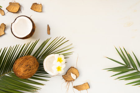 Summer flat lay scene with palm leaves and frangipani flowers with coconuts on wooden background with copy spaceの写真素材
