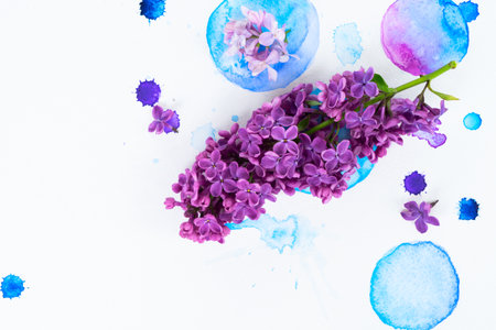 Fresh lilac flowers frame over white background with watercolor paint splashes, flat lay flower composition with copy spaceの写真素材