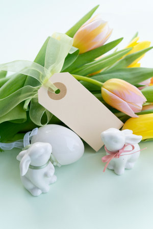 Easter scene with colored eggs in nest with tulips and bunny, copy space on paper noteの写真素材