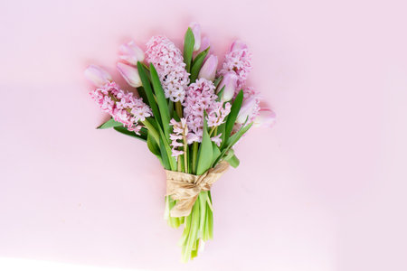 Easter scene with fresh tulips and hyacinth flowers bouquet over pink backgroundの写真素材