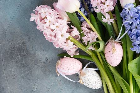 Easter scene with fresh tulips and hyacinth flowers with olored Easter eggs over gray backgroundの写真素材