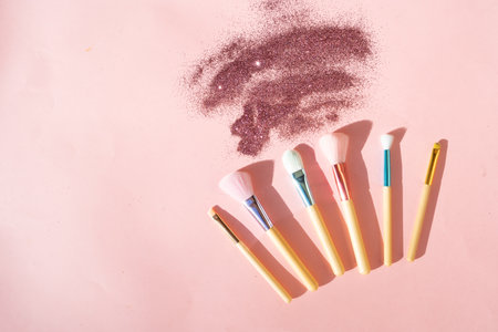 Minimal modern cosmetic scene with set of make up brushes set over pink background with glitter and shadow overlay, copy spaceの写真素材