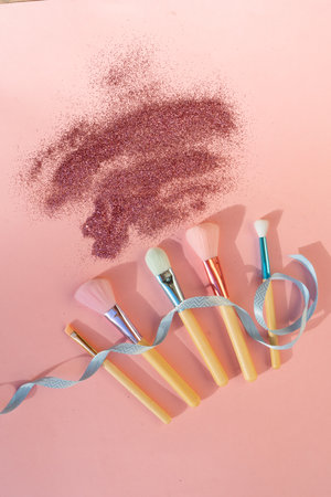 Minimal modern cosmetic scene with set of make up brushes set over pink background with glitter and shadow overlayの写真素材