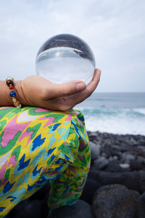 woman meditating on wild beach shore and holding crystal ballの写真素材