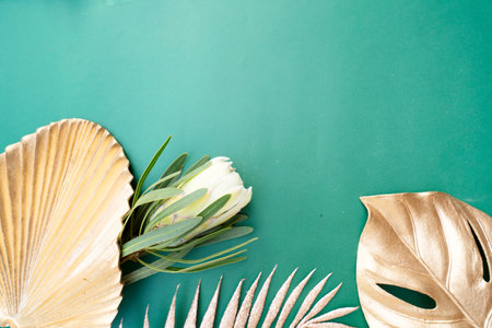 Tropical leaves and flowers over green background, summer background with copy spaceの写真素材