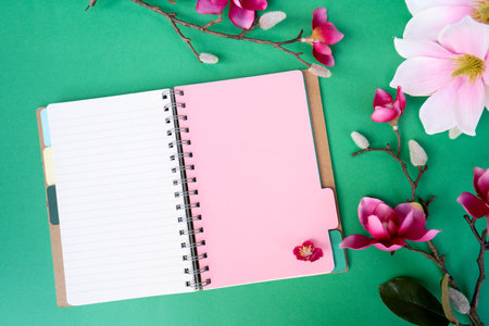Blooming pink magnolia tree branch with flowers against green background, open notebook page for copy spaceの写真素材
