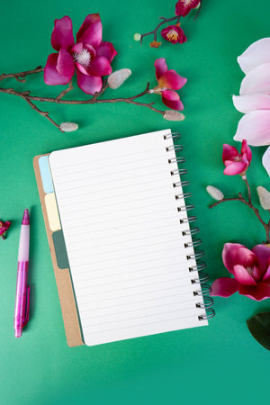 Blooming pink magnolia tree branch with flowers against green background, open notebook page for copy spaceの写真素材