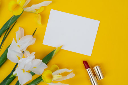 Minimal modern cosmetic scene with set of make up brushes, cosmetics and flowers set over yellow background, copy spaceの写真素材