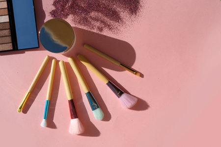 Minimal modern cosmetic scene with set of make up brushes set over pink background with glitter and...