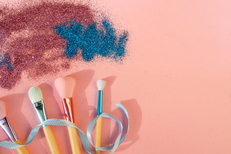 Minimal modern cosmetic scene with set of make up brushes set over pink background with glitter and shadow overlayの写真素材