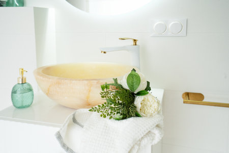 White tap and stone water basin in white bathroom with cosmeticsの写真素材